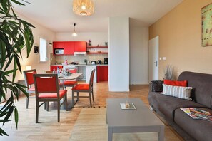 Ein modernes Wohnzimmer mit Sofa, Couchtisch und Essbereich mit Stühlen.