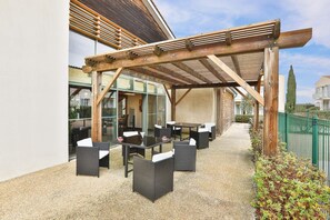 Un patio al aire libre con mobiliario de mimbre y una pérgola de madera.
