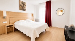 A neatly arranged bedroom with a bed, bedside tables, a mirror, and a wall-mounted artwork. - Zenao Appart'hôtels Sainte-Soulle (Sainte-Soulle)