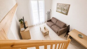 A modern living room with a sofa, a coffee table, a desk with a computer, and a painting on the wall. - Zenao Appart'hôtels Sainte-Soulle (Sainte-Soulle)