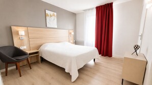 A hotel room with a bed, a chair, a desk, a lamp, a red curtain, and a small table with a globe. - Zenao Appart'hôtels Sainte-Soulle (Sainte-Soulle)