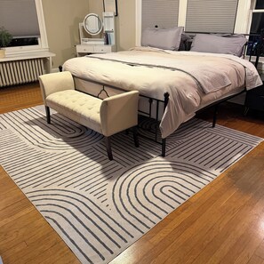 Une chambre à coucher comprenant un lit, une chaise, une table de chevet avec un miroir et un radiateur.