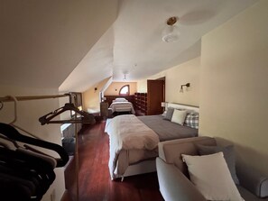 A bedroom with a large bed, a sofa, a wardrobe, and a hanging rack.