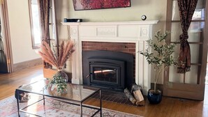 A living room with a fireplace, a flat-screen TV, and a large abstract painting. - Historic 6 bedroom Home Downtown Juneau
526 Main Street (Juneau)