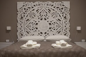 A bed with a decorative headboard, two pillows, and rolled towels on the bed. - Naples Holiday House with Private Terrace, near Station, Metro, Airport (Napoli)