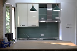 A modern kitchen with white cabinets, green backsplash, stainless steel appliances, and pendant lighting. - Naples Holiday House with Private Terrace, near Station, Metro, Airport (Napoli)