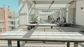 Eine Dachterrasse mit Pool, Liegestühlen und Blick auf die Stadtlandschaft.
