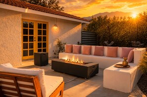 Eine Terrasse mit Feuerstelle, Sitzgelegenheiten im Freien und einer Tür zum Innenbereich.