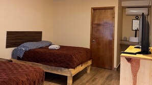 Une pièce avec deux lits en bois, une commode en bois, une porte et un luminaire au plafond.