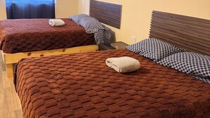 Une chambre avec deux lits, chacun doté d’une tête de lit, une fenêtre avec un rideau et une prise électrique au mur.