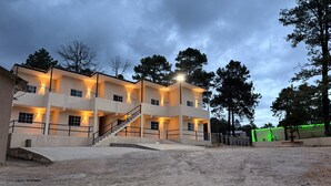Un immeuble à plusieurs étages doté d’un escalier, de balcons et d’une zone au rez-de-chaussée dallée.