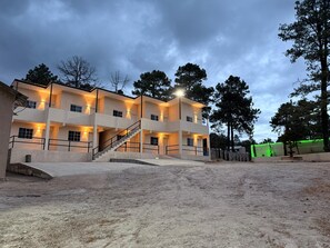 Un edificio de varios pisos con escaleras, balcones y una zona pavimentada en la planta baja.