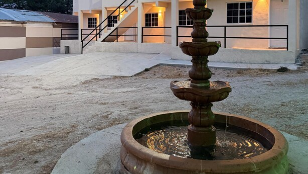 Un immeuble à plusieurs étages doté d’un escalier central, d’une fontaine et d’un espace extérieur bien entretenu.