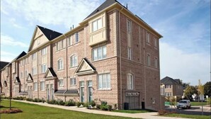En fleretagers murstensbygning med en symmetrisk facade, store vinduer og en central indgang.