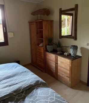 A bedroom with a bed, wooden wardrobe, and a window with a view.