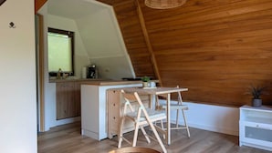 Eine kompakte Küche mit Holzbalkendecke, einem Essbereich mit zwei Stühlen und einem kleinen, weißen Schrank.