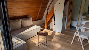 Ein gemütliches Schlafzimmer im Loft-Stil mit Holzbalkendecke, einer Couch, einem kleinen Tisch und einem Sessel.