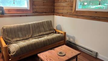 Interior de madera con sofá, una mesita y suelo de madera, además de un ventanal con vistas.