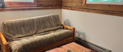 Interior de madera con sofá, una mesita y suelo de madera, además de un ventanal con vistas.
