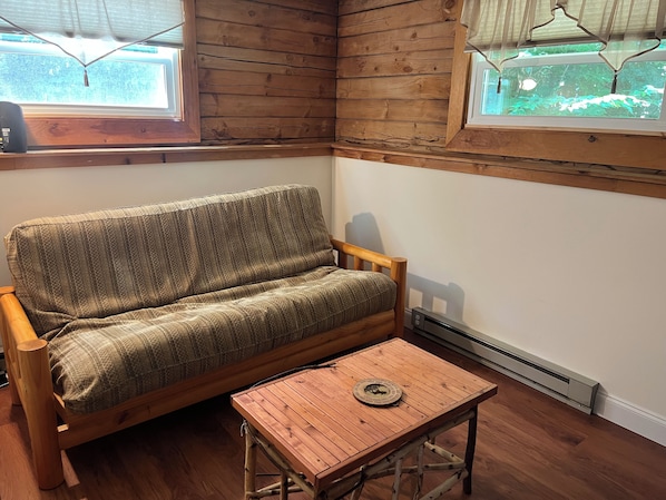 Ein Holzinnenraum mit einer Couch und einem kleinen Tisch, Holzböden und einem Fenster mit Blick.
