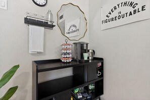 Un piano di lavoro in cucina con una macchina da caffè, un oggetto decorativo e uno scaffale con una bottiglia.