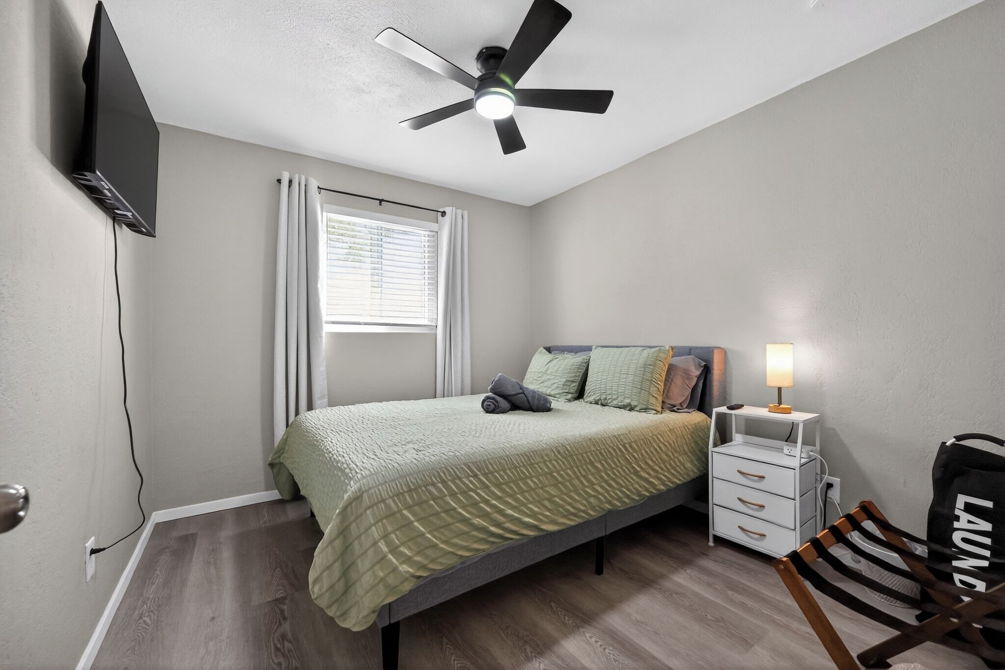 Une chambre à coucher avec un lit, un ventilateur de plafond, une table de chevet, une lampe et une chaise.