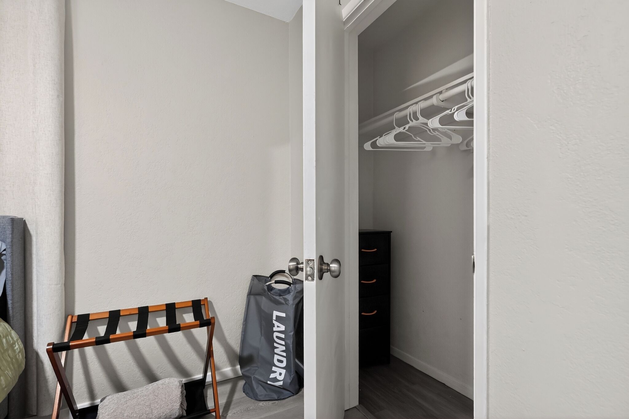 Une pièce avec une porte donnant sur un placard, un étendoir et un sac à linge.
