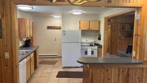 Una cocina con gabinetes de madera, un refrigerador, estufa y cafetera.