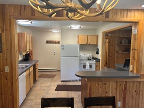 Une cuisine avec des meubles en bois, un réfrigérateur, une cuisinière et une machine à café.