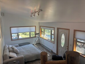 A bedroom with a bed, a desk, a telescope, and large windows. - RIVER SIDE walking distance to town/the lake & Rocky Mnt Natl Park! 3-bedroom (Grand Lake)