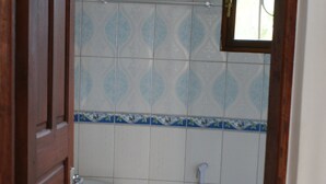 Casa de banho com sanita, bidé e uma pequena janela.