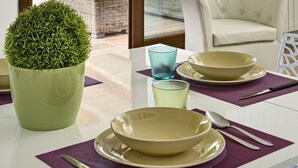 Ein Essbereich mit Tisch für zwei Personen, einem Blumentopf und Blick auf Pool und Berge durch eine Glastür.