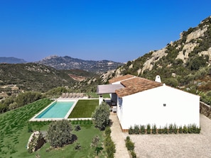 Eine weiße Villa mit Swimmingpool, Garten und Bergblick.