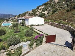 Eine Villa mit Swimmingpool, umgeben von einem Garten und einer Steinmauer.