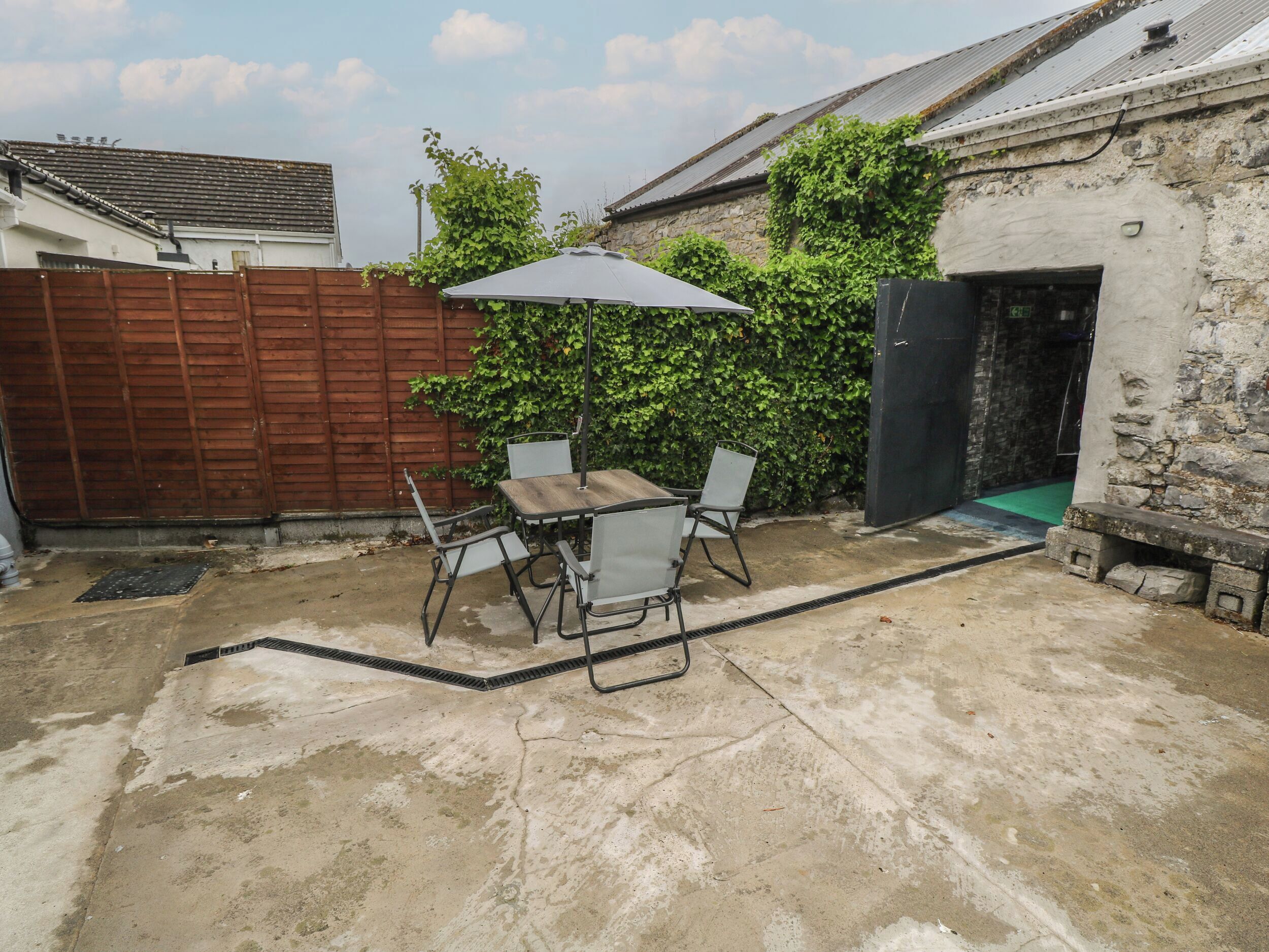 A patio area with a table and chairs, a wooden fence, and a stone wall.