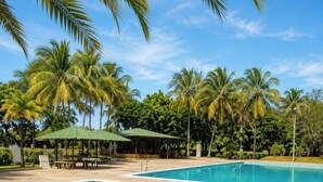 A swimming pool with lounge chairs and a gazebo, surrounded by palm trees. - Modern 2 Bedroom apartment in Juangriego with Pool (Juangriego)