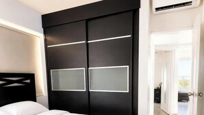A modern bedroom with a large bed, a dark headboard, and a sliding door with frosted panels. - Modern 2 Bedroom apartment in Juangriego with Pool (Juangriego)