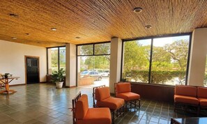 Une pièce spacieuse avec un plafond en bambou, de grandes fenêtres et des sièges de couleur orange.