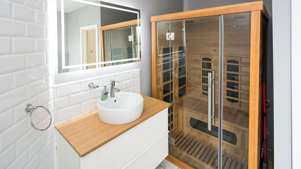 Un bagno con un lavandino bianco, uno specchio e una cabina doccia in vetro.