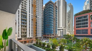 Un immeuble résidentiel de grande hauteur doté de nombreux balcons, d’une grue de construction et d’un jardin aménagé sur le toit.