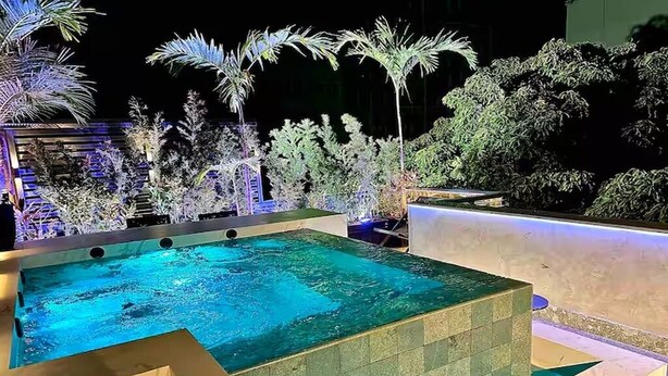 A rectangular swimming pool with a tiled edge, surrounded by various plants and trees. - Luxury Penthouse with Private Heated Pool & Christ the Redeemer Views in Ipanema (Rio de Janeiro)