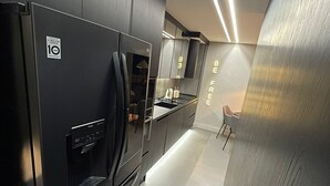 A modern kitchen with a black refrigerator, a built-in oven, and a microwave. - Luxury Penthouse with Private Heated Pool & Christ the Redeemer Views in Ipanema (Rio de Janeiro)