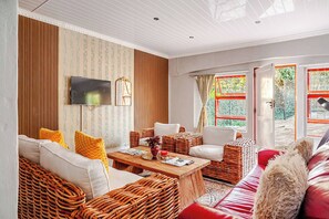 Sala de estar com móveis de vime, uma TV de tela plana e uma janela grande com vista.