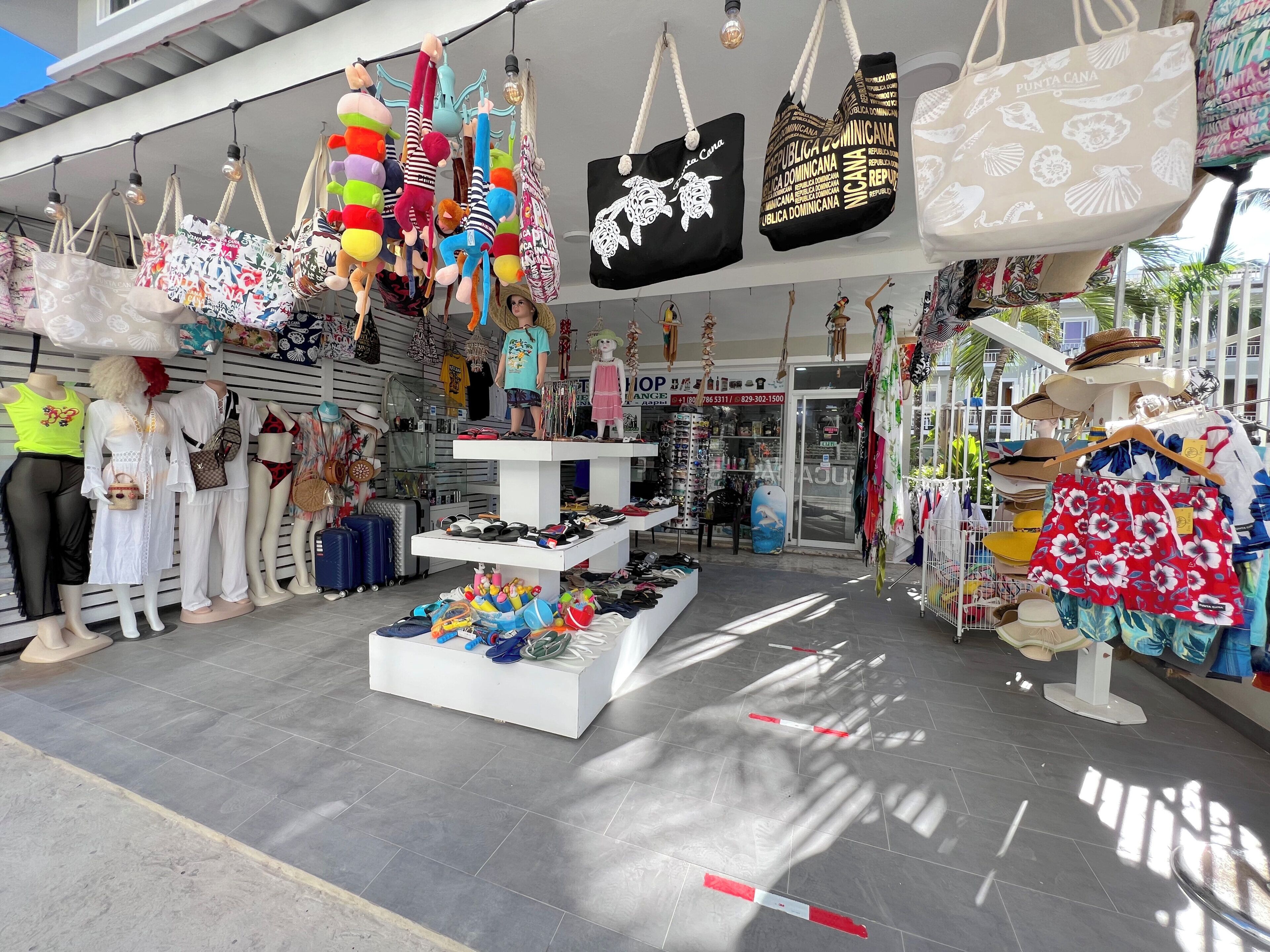 Tienda con bolsas colgantes, maniquíes y una variedad de zapatos a la vista.