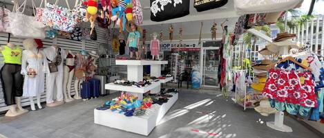 Tienda con bolsas colgantes, maniquíes y una variedad de zapatos a la vista.