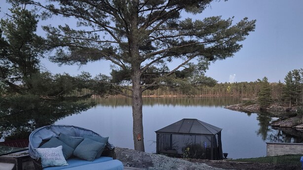 A wooden deck with a wicker sofa, a small shed, and a pond. - Northern Paradise on the lake with water activities, Pet-friendly (Hagar)
