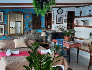 A room with a sofa, a dining table with chairs, a mirror, and a fireplace. - Seaside Ntounas Apartments - Cretan Double Nest (Agios Nikolaos)