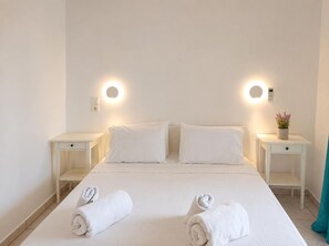 A hotel room with a bed, two bedside tables, a wall-mounted light, and a small potted plant. - Votsalon Beach House - Sea View Hideaway Zakynthos (Zakynthos)