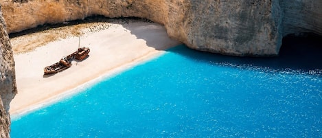 Una playa con agua azul cristalina, una orilla arenosa y un bote.