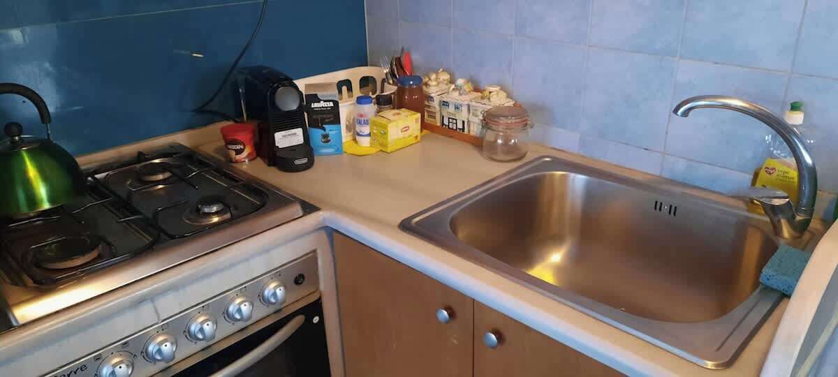 A compact kitchen with a gas stove, a sink, and various kitchen items on the countertop.